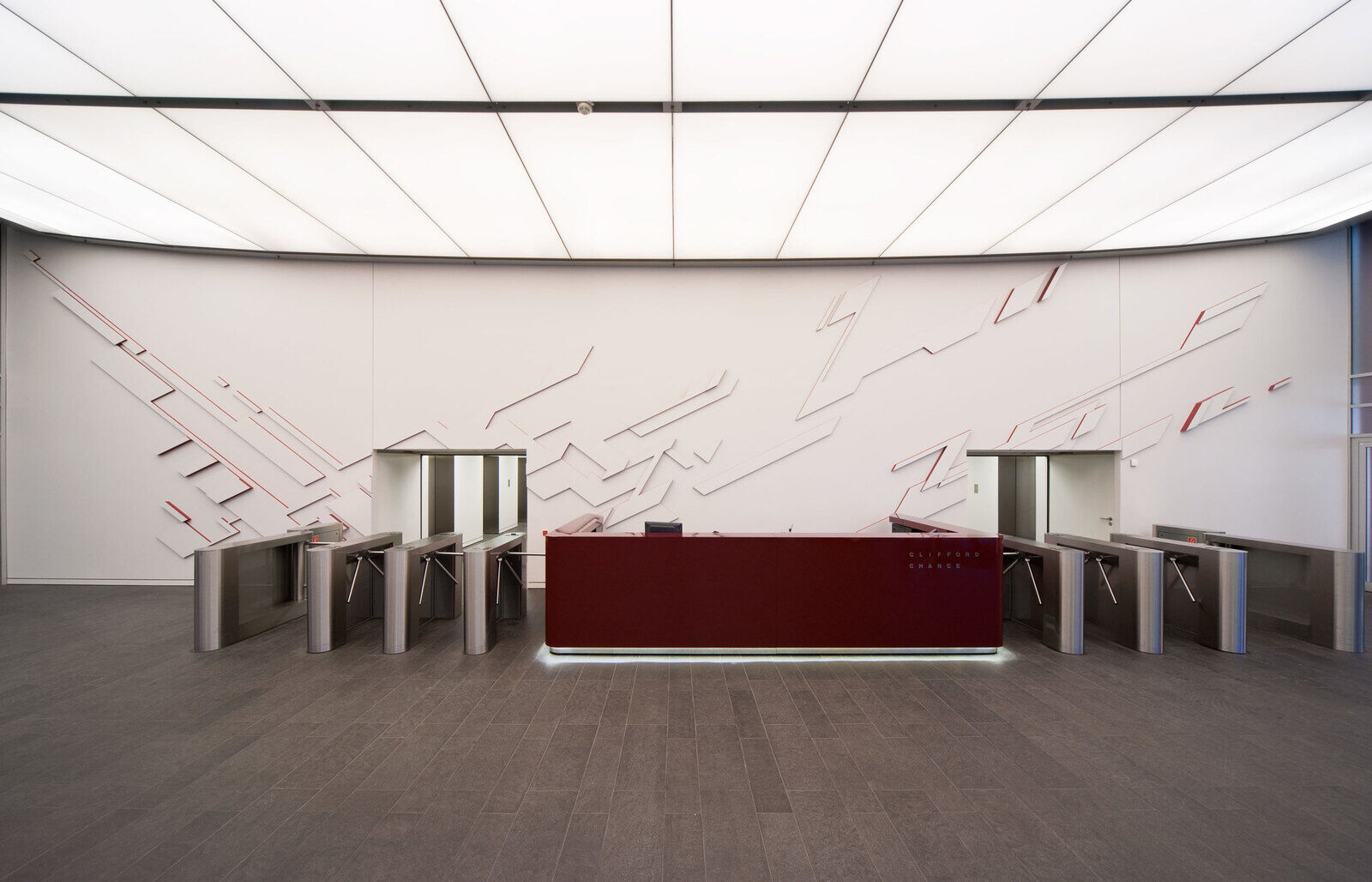 Foyer des FBC Frankfurter B&uuml;ro Center mit dreistufigem Wandrelief von Heiko Zahlmann und dunkelrotem Empfangstresen